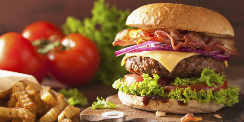 Hamburguesa con queso, bacon crujiente, cebolla caramelizada, salsa y pan tostado