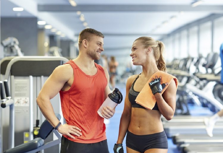 Un hombre y una mujer se sonríen en el gimnasio, instrucciones ligar en el gimnasio (IStock)