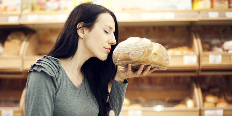 Mujer oliendo una hogaza de pan (iStock)