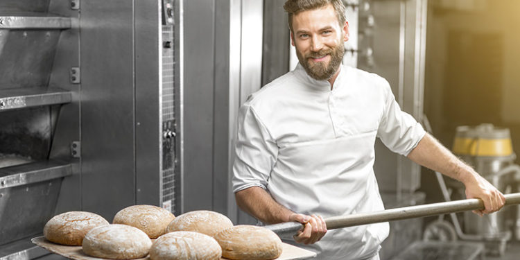 Panadero artesano sacando el pan del horno (iStock)